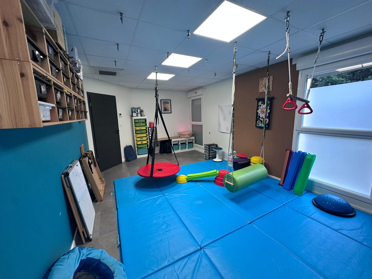 Salle d'intégration neurosensorielle : tapis, balançoires et trapèzes suspendus